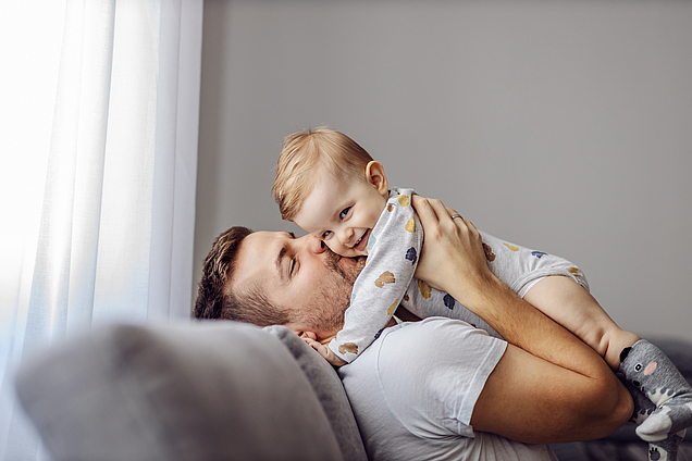 Vater in Vaterschutz hebt Baby in die Höhe