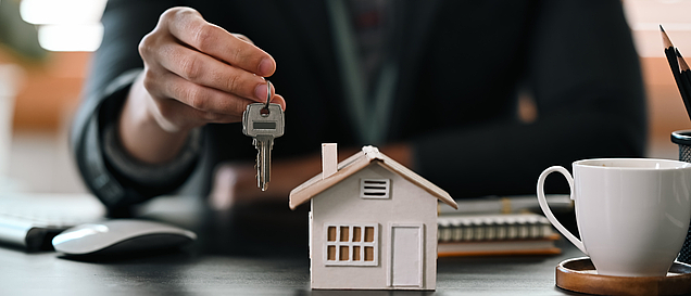Verkäufer einer Immobilie übergibt Schlüssel und Kaufvertrag